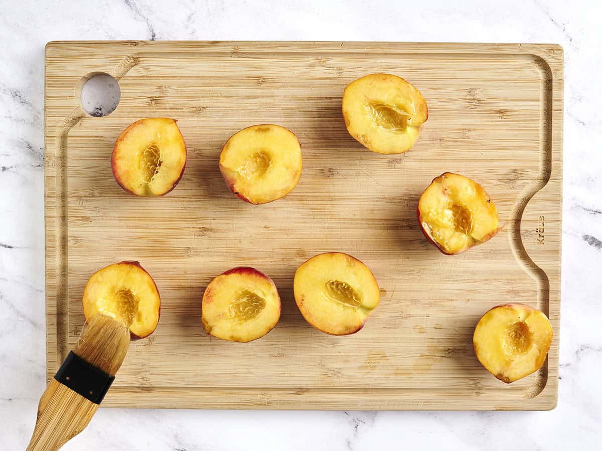 Eine Bürstenbürste, die Pfirsichhälften mit Öl.