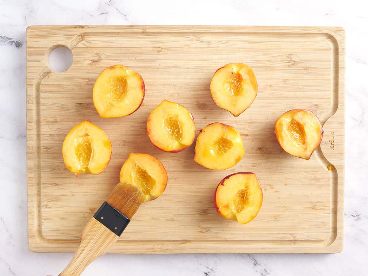 Pfirsichhälften werden mit Öl gebürstet.