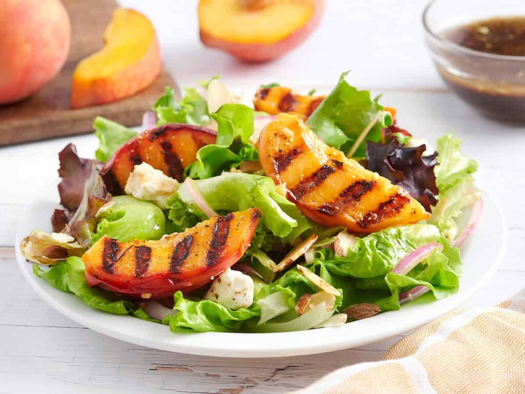 Side view of a grilled peach salad on a plate.