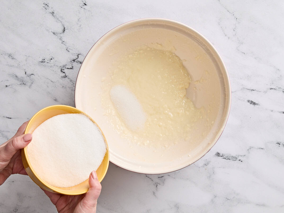 Zucker wird in geschlagene Butter und Öl gegossen.