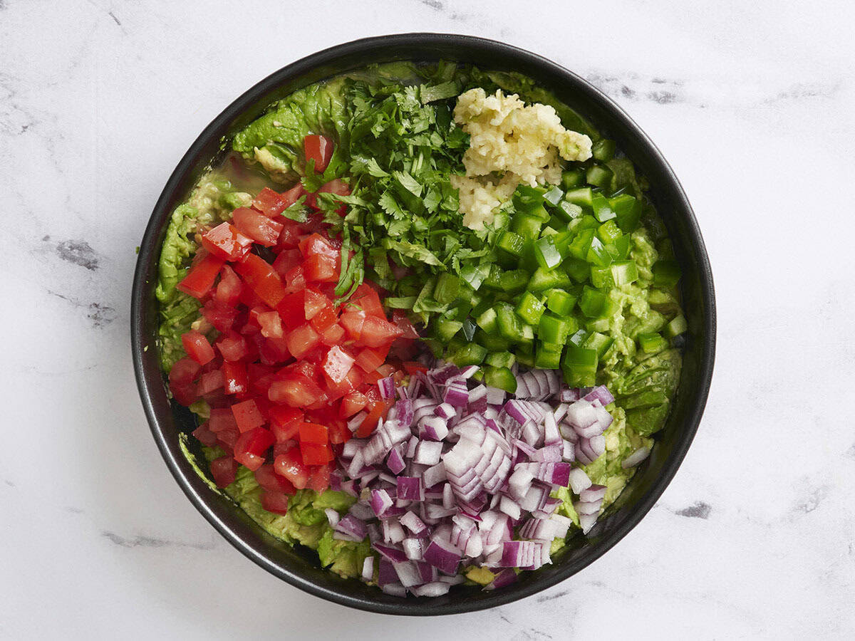 Rote Zwiebel, gehackter Koriander, Tomaten, grüner Paprika und Knoblauch, der Avocado gedrückt wurde.