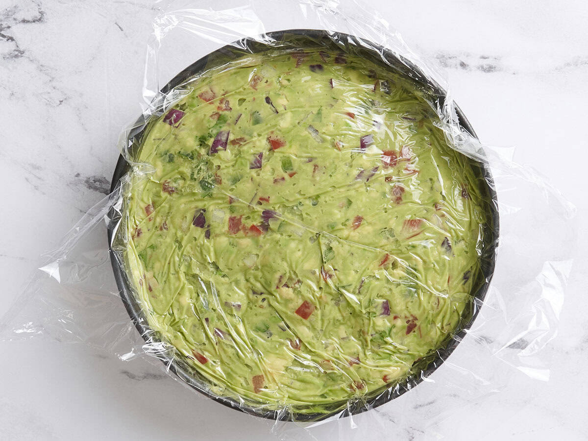 Guacamole in einer Schüssel mit Plastikfolie.