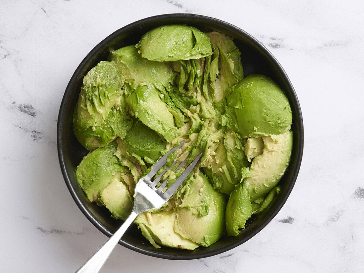 Eine Gabelpüree -Avocado -Hälften in einer Schüssel.