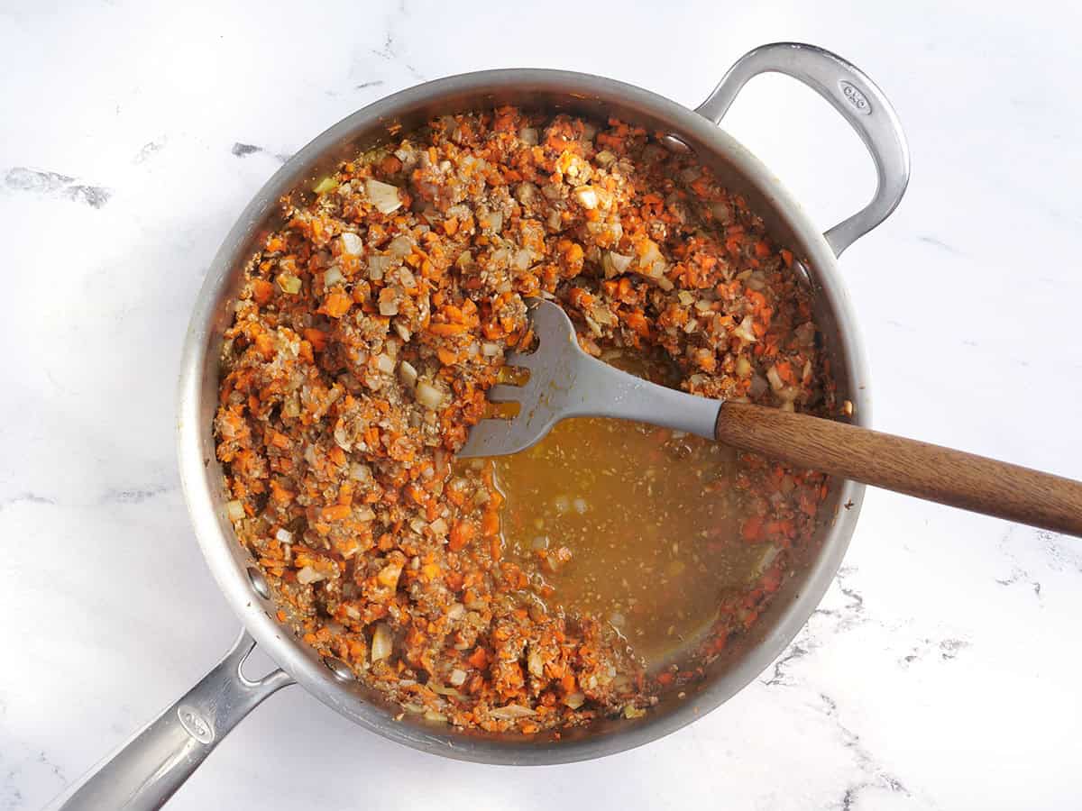 Linsen-Hackbraten-Zutaten in einer Pfanne mit einem Pfannenwender anbraten.