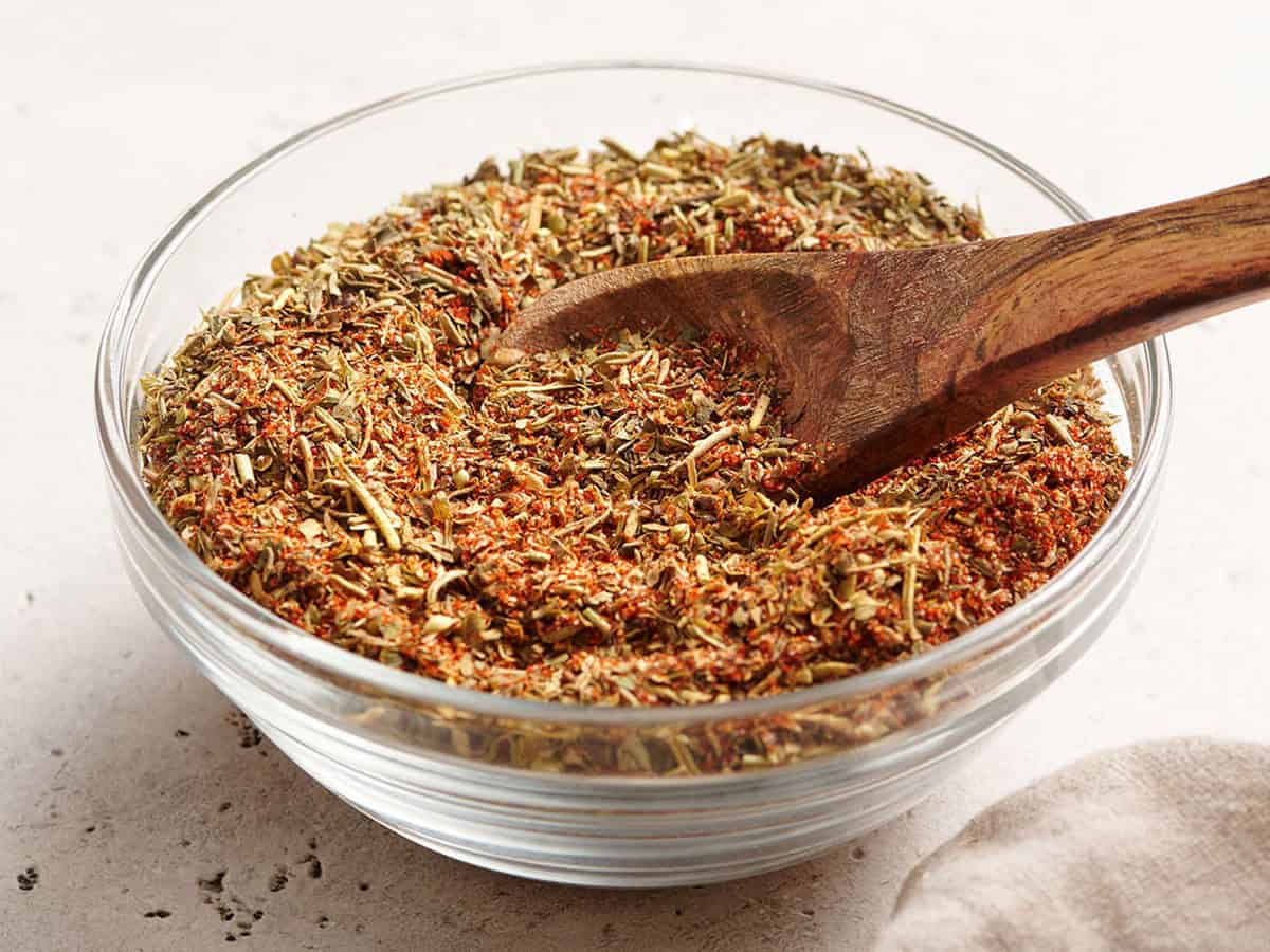 Seitenansicht einer Schüssel mit Geflügelgewürz mit einem Holzlöffel.