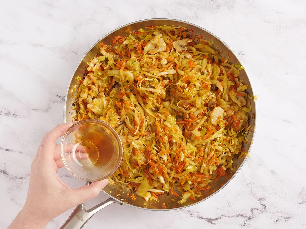 Sesamöl wird in eine Pfanne mit sautiertem Gemüse gegossen.