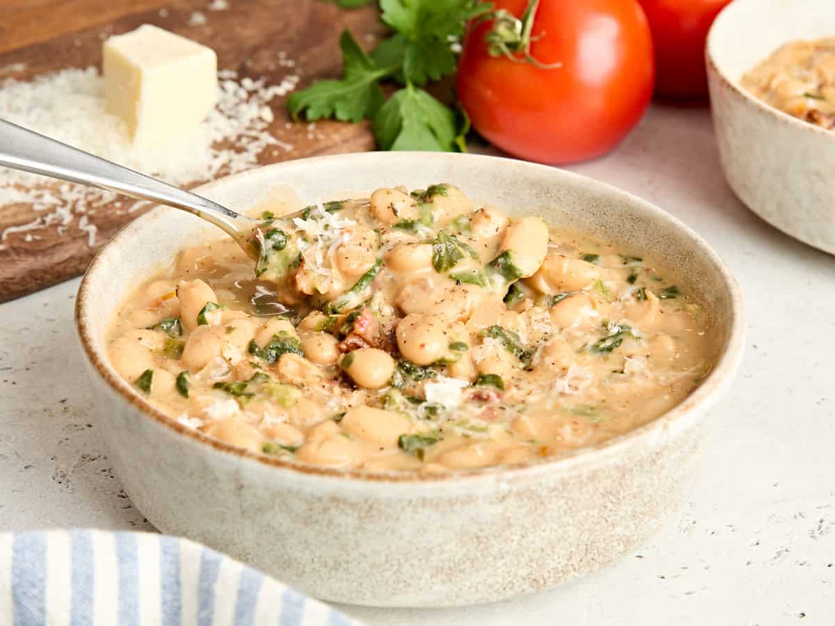 Seitenansicht einer Schüssel mit weißen Bohnen „Marry Me“ mit einem Löffel.