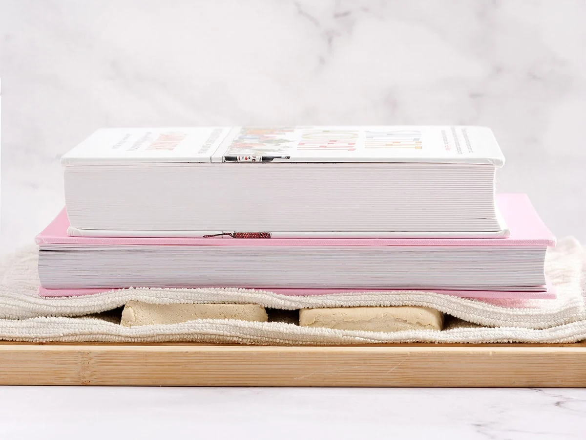 Tofu wird mit Kochbüchern gepresst.