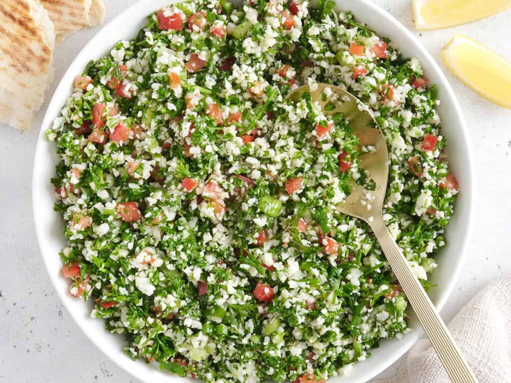 Overhead view of a bowl of cauliflower tabbouleh with a spoon.