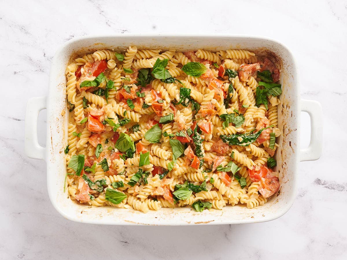 Fertig gebackene Feta-Nudeln in einer mit Basilikum belegten Auflaufform.