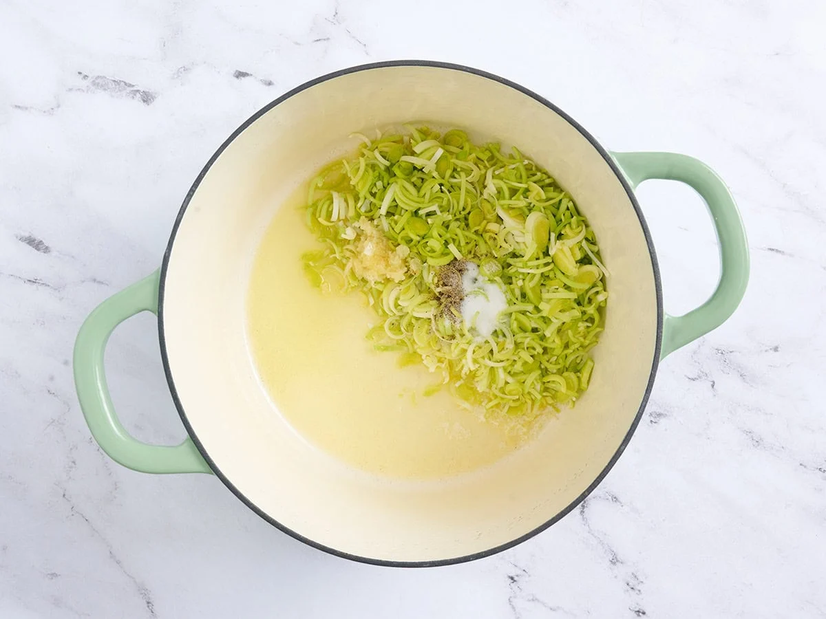 Zerlassene Butter und Öl in einem Topf mit gehacktem Lauch und Knoblauch.