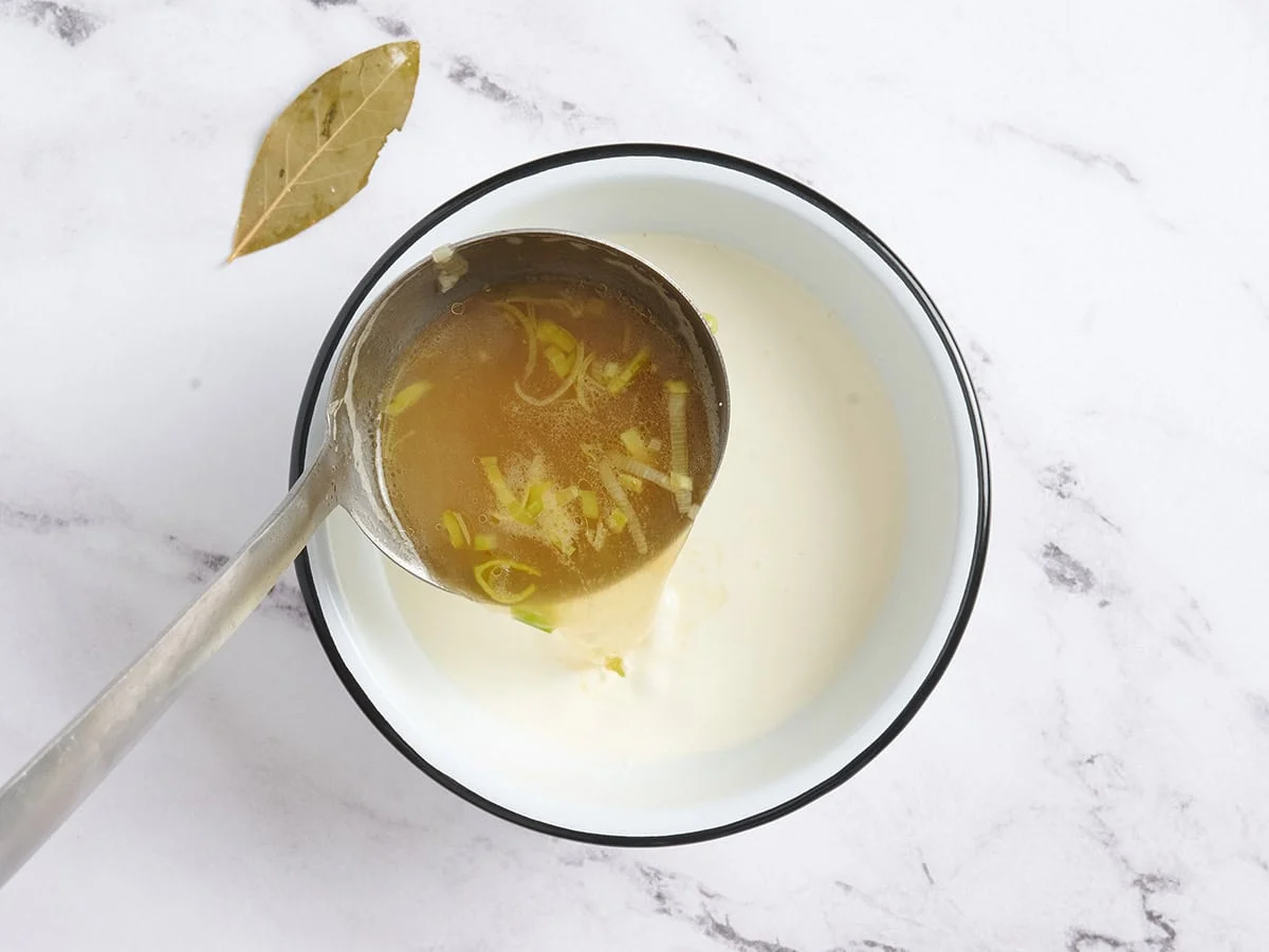 Heiße Suppe wird in eine Schüssel mit Sahne gegossen.