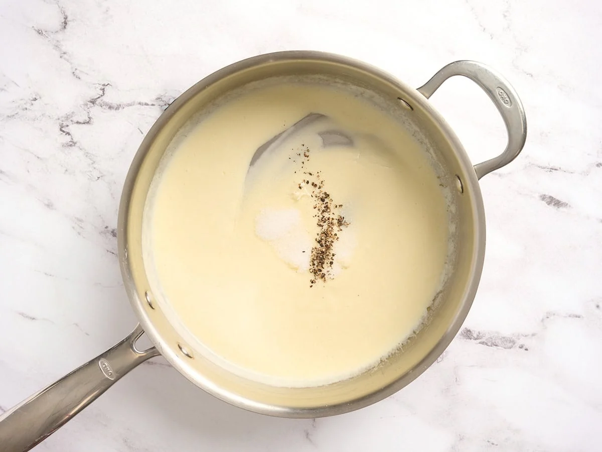 Eine Sahnesauce in einer Pfanne mit Gewürzen.