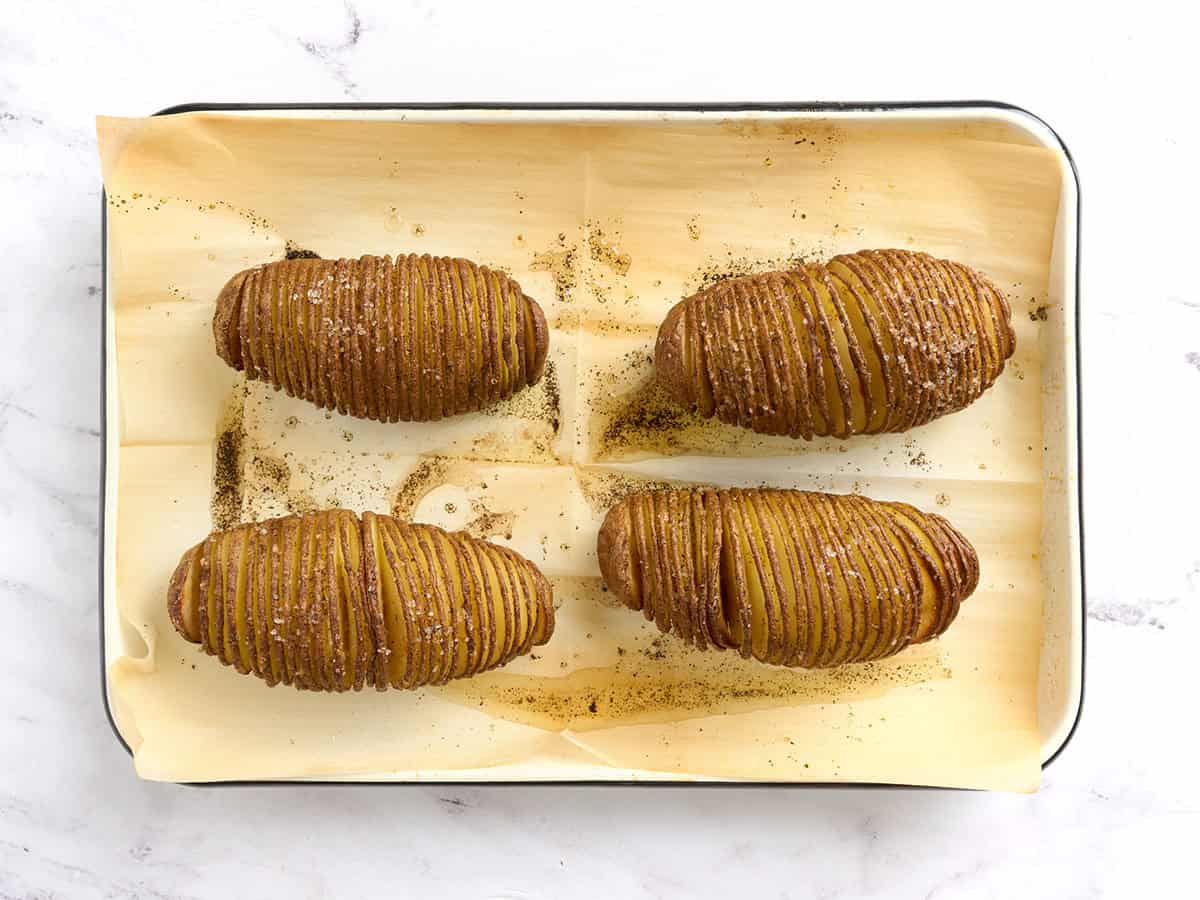 Hasselback-Kartoffeln auf einem mit Backpapier ausgelegten Backblech.