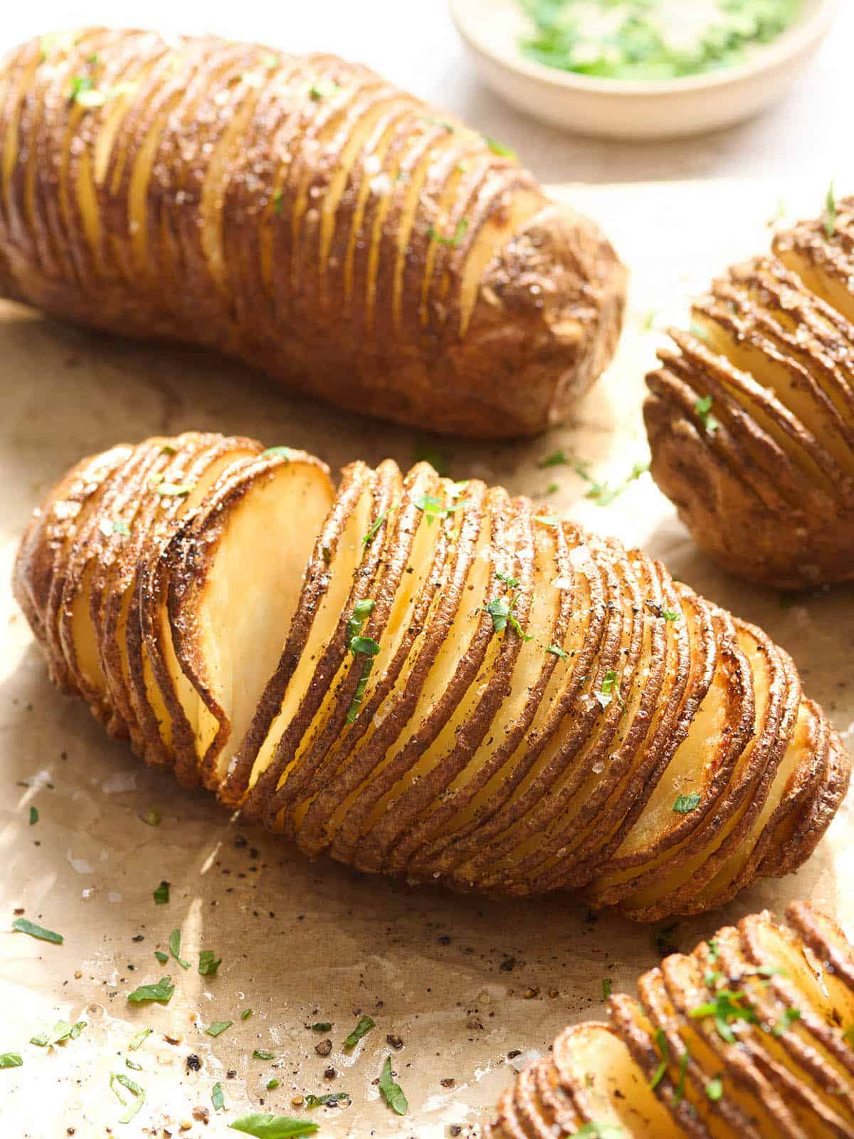 Seitenansicht von Hasselback-Kartoffeln auf Pergamentpapier.