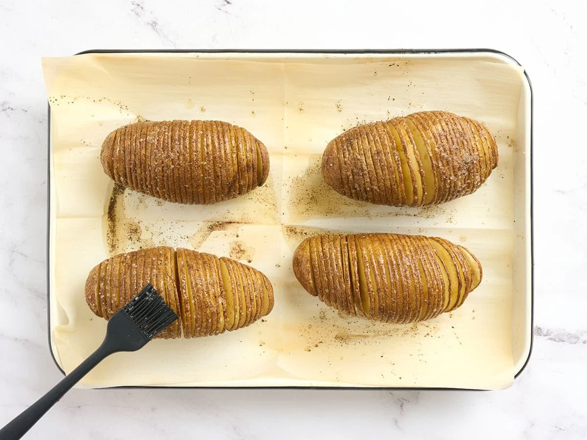 Hasselback-Kartoffeln werden während des Backens mit gewürztem Öl bestrichen.