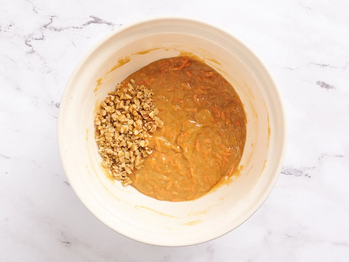 Walnüsse zum Karottenkuchenteig in einer Rührschüssel hinzufügen.