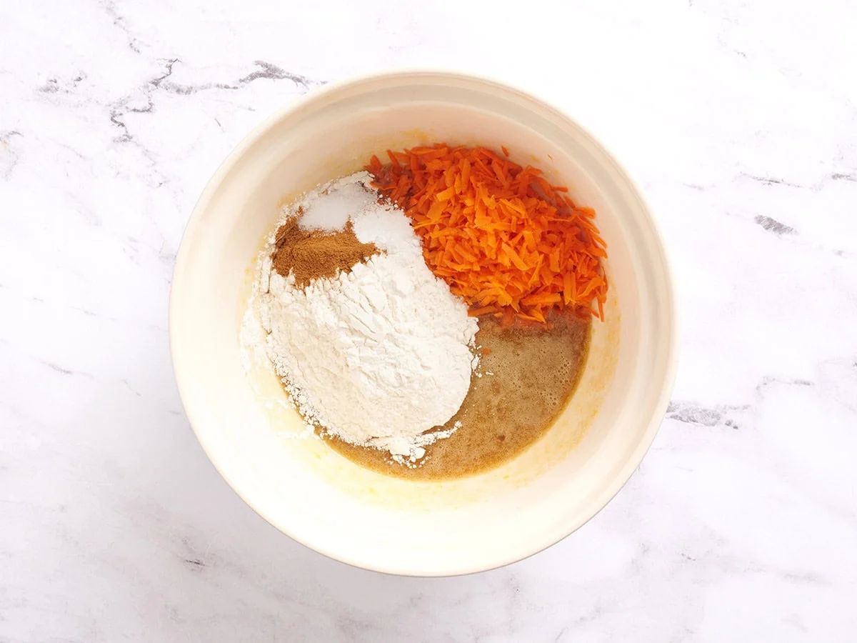 Mehl, Gewürze, geriebene Karotten und Kuchenteig in eine Schüssel geben.