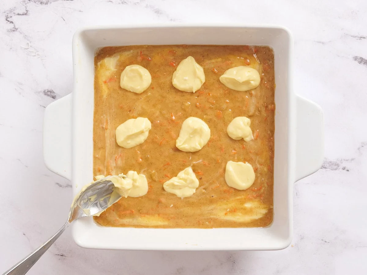 Für Karottenkuchenriegel werden dem Teig Käsekuchenkleckse hinzugefügt.