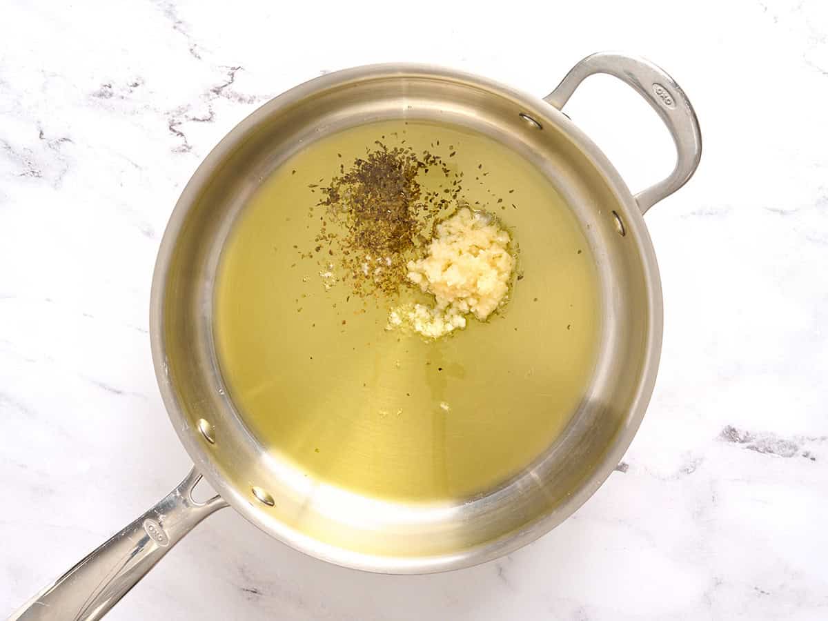 Knoblauch, Kräuter und Öl in einer Pfanne.