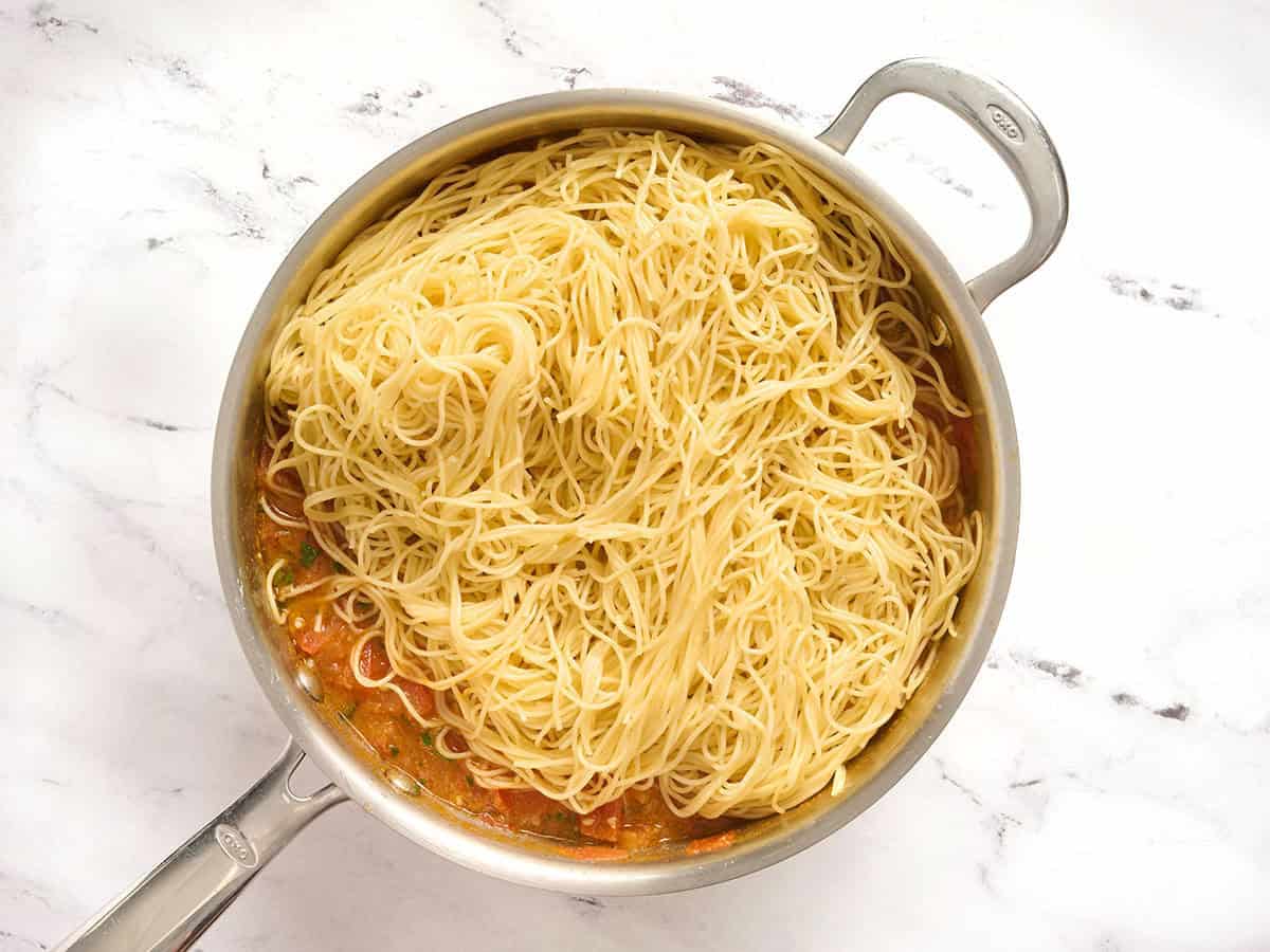 Engelshaarnudeln in einer Pfanne mit Gemüse hinzufügen.