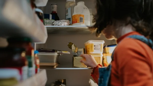 Ein Kind öffnet einen Kühlschrank und greift hinein.