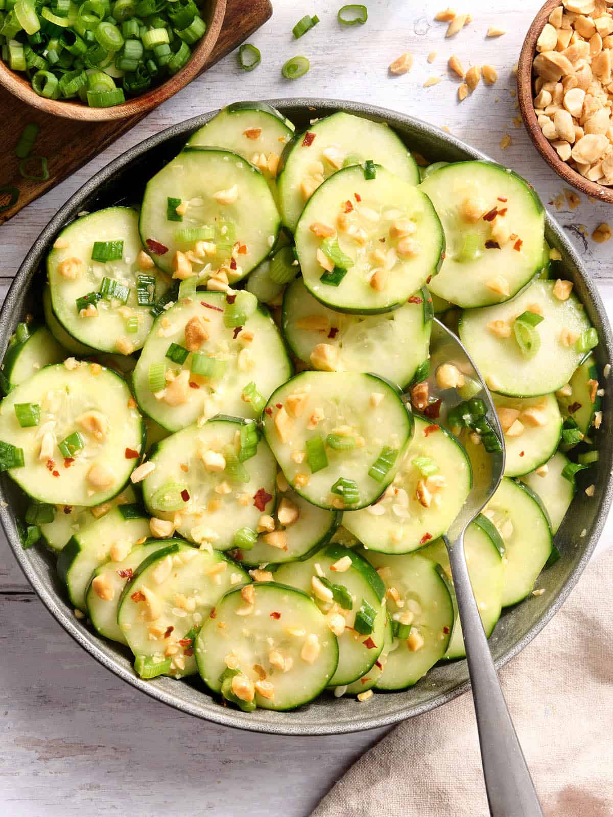 Blick von oben auf eine Schüssel Sesam-Gurkensalat mit einem Löffel.