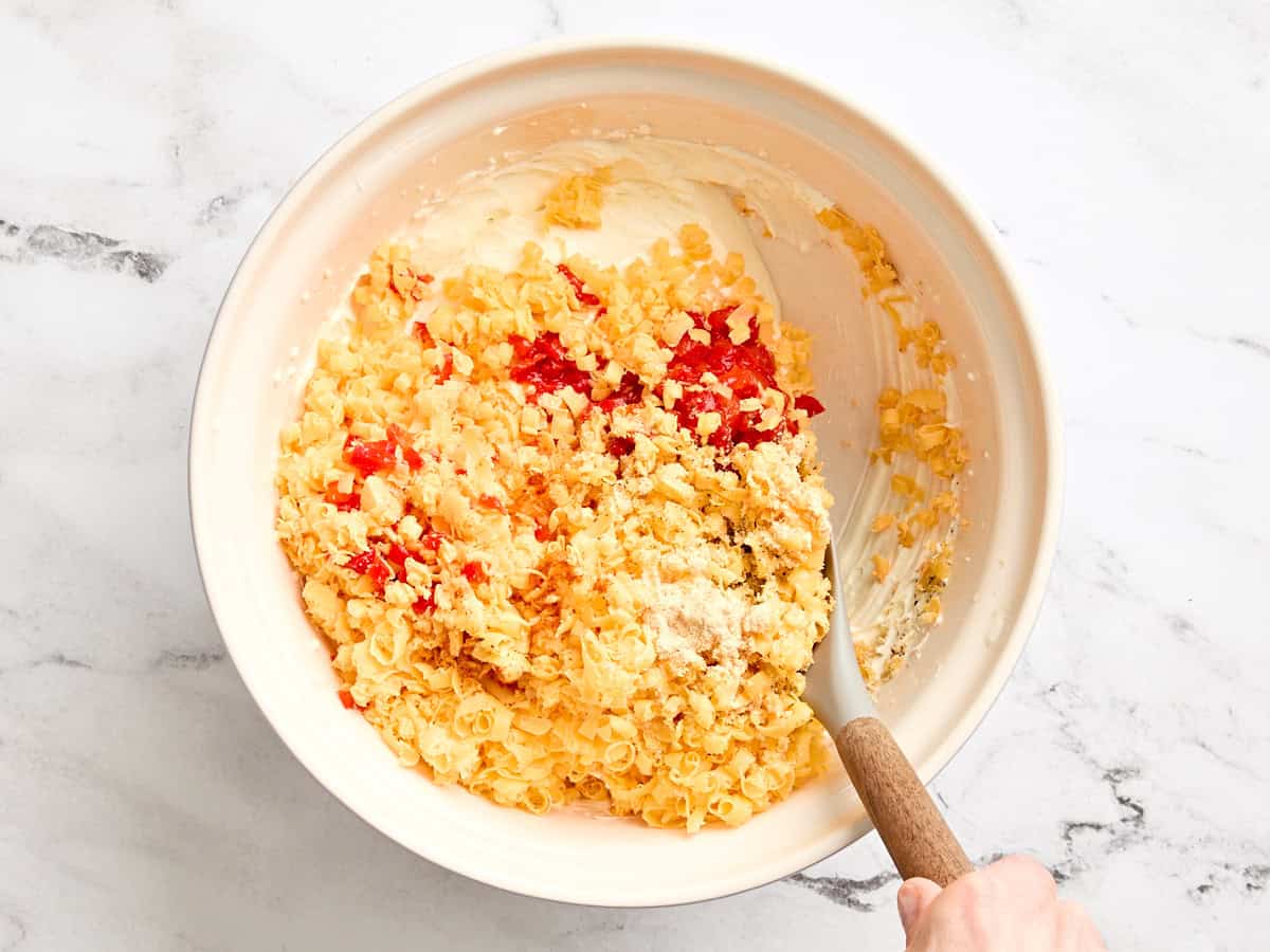 Geriebener Cheddar und gehackte Pimente werden in eine Schüssel mit Mayonnaise und Frischkäse gegeben.
