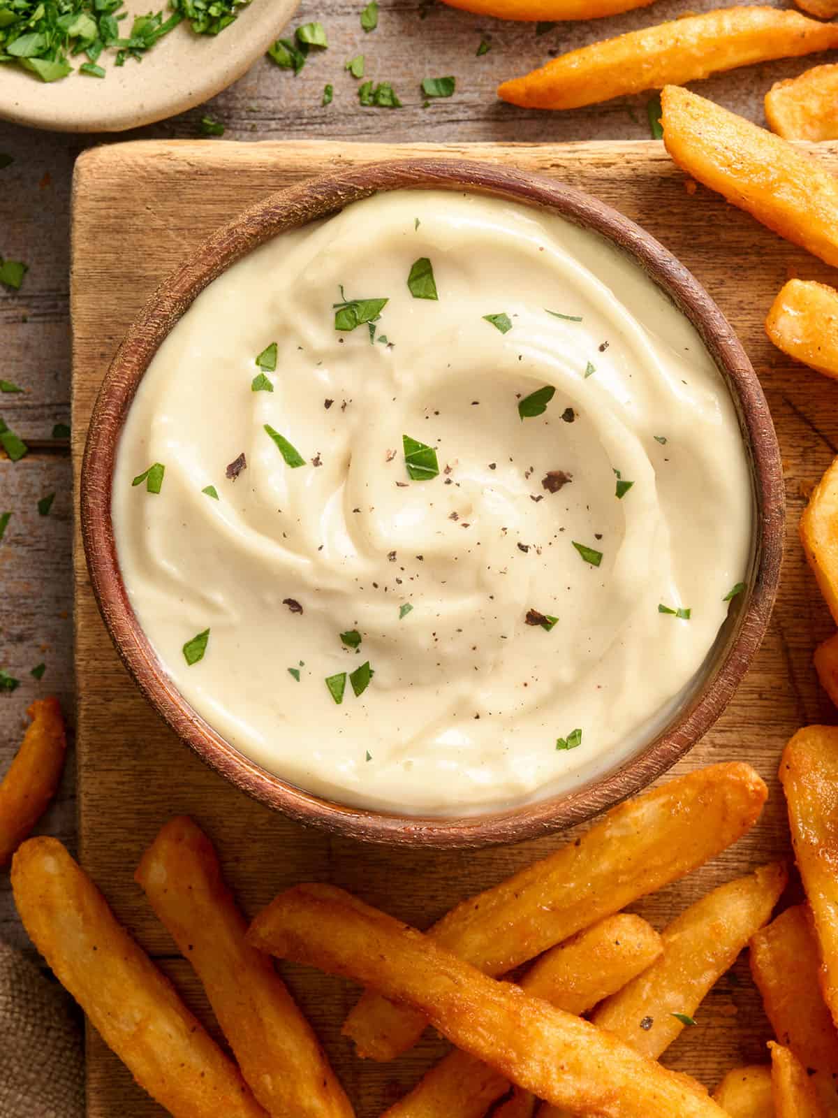 Blick von oben auf eine Schüssel hausgemachte Knoblauch-Aioli mit Pommes Frites.