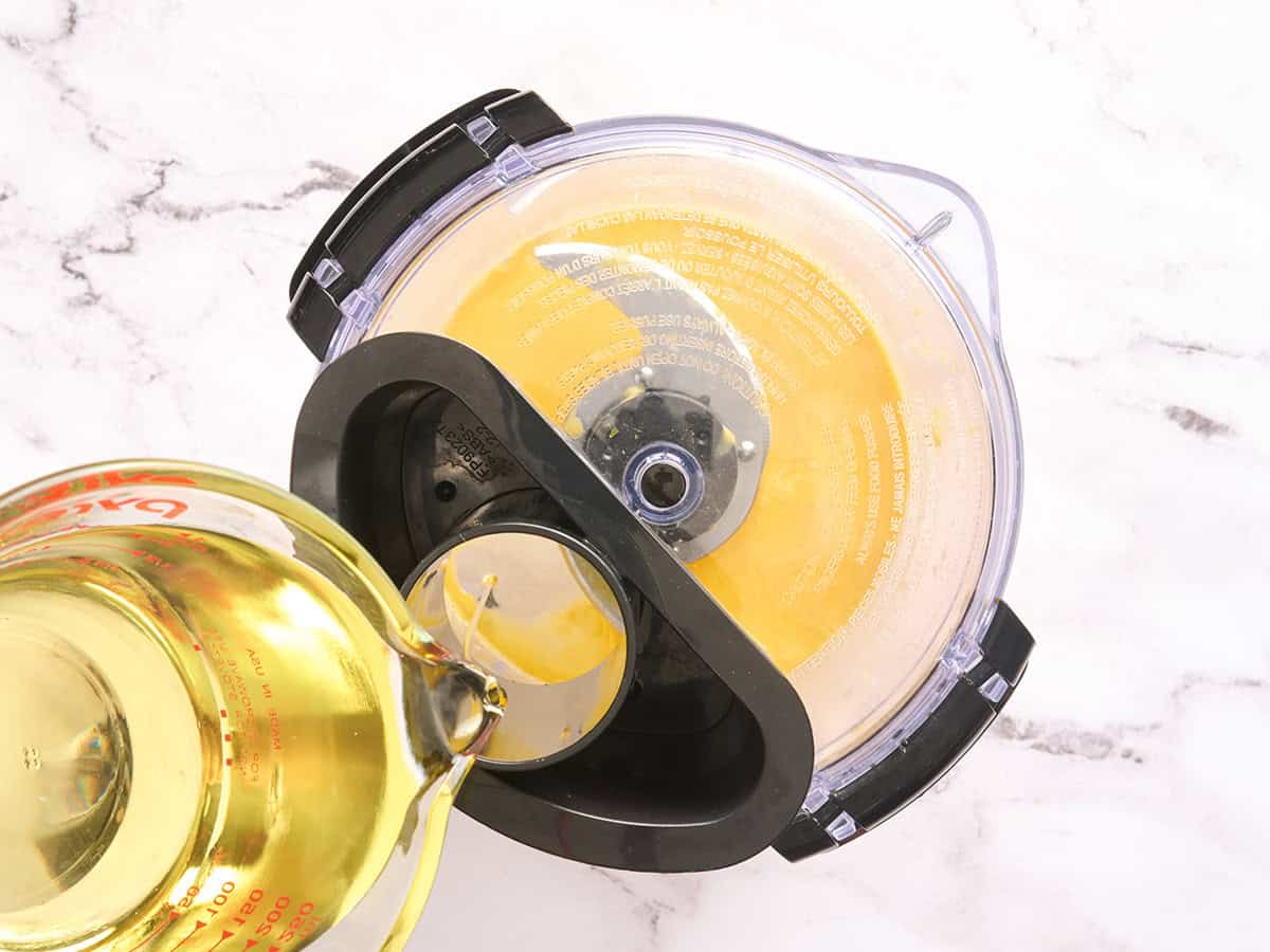 Öl wird in eine Küchenmaschine geleitet, um eine Emulsion für Knoblauch-Aioli herzustellen.