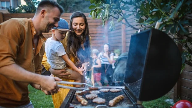 Junge glückliche Familie bei einer Grillparty im Hinterhof