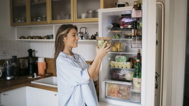 Frau nimmt Essen aus dem Kühlschrank