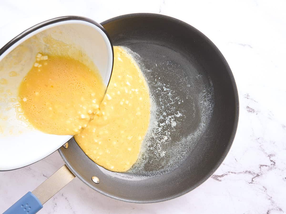 Hüttenkäse-Ei-Mischung wird in eine Pfanne gegossen.