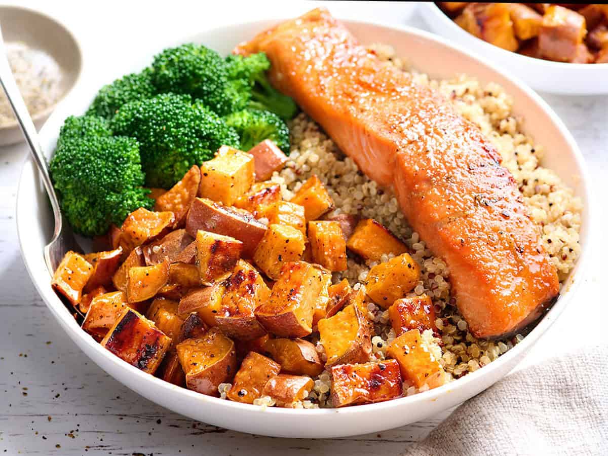 Vorderansicht einer Schüssel Quinoa mit Lachsfilet, gerösteten Süßkartoffeln und Brokkoli.