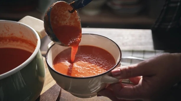 Eine Person serviert eine Schüssel Tomatensuppe